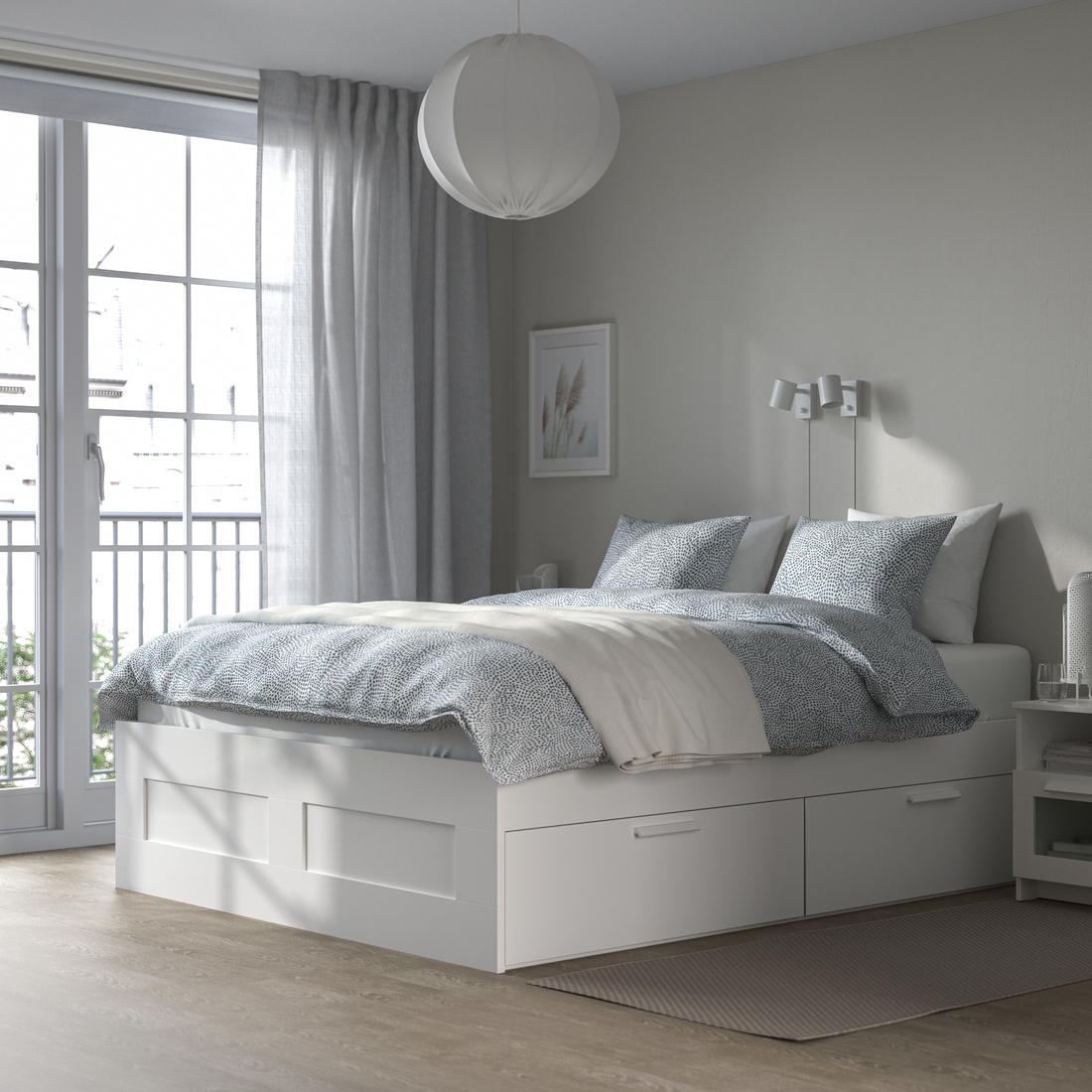 White bed frame with storage drawers and light blue bedding in a bright bedroom.
